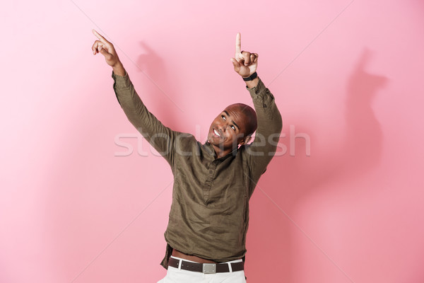 Szczęśliwy Afryki człowiek wskazując w górę różowy Zdjęcia stock © deandrobot