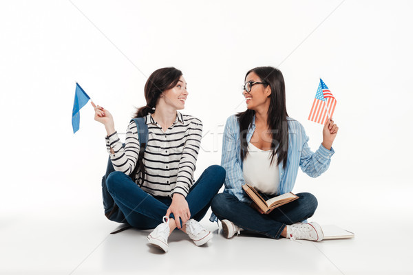 Two young female students waving us flags while sitting Stock photo © deandrobot