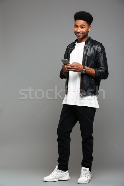 Stock photo: Full length photo of happy fashionable afro american man holding