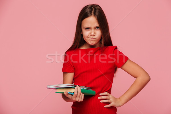 Unhappy girl in red dress holding book and looking camera isolated Stock photo © deandrobot