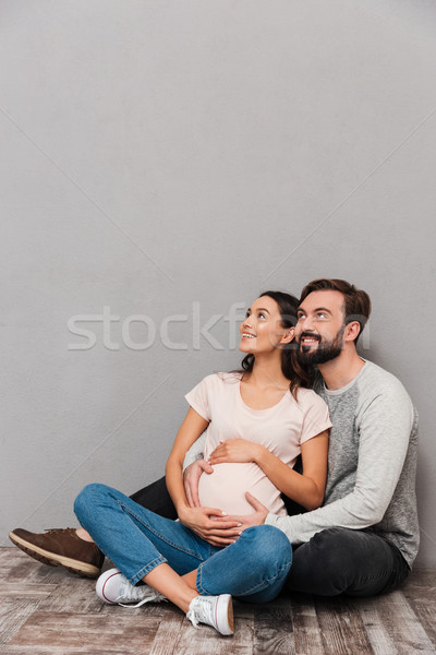 Portrait of a cheerful young man hugging his pregnant wife Stock photo © deandrobot