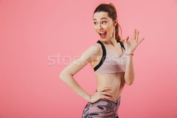 Sportswoman with arm on hip while looking and waving back Stock photo © deandrobot