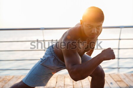 Relaxed young man meditating while sitting on a fitness mat Stock photo © deandrobot