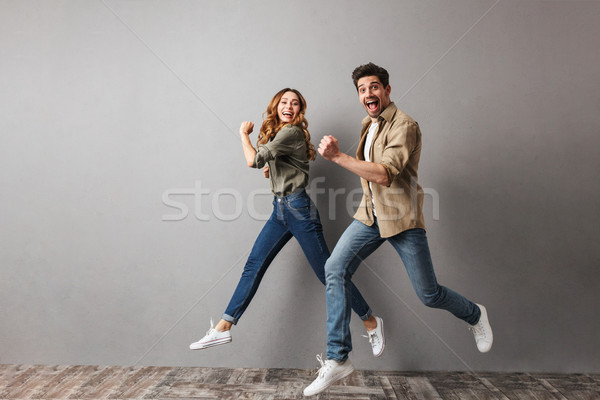 Full length portrait of a happy young couple jumping Stock photo © deandrobot