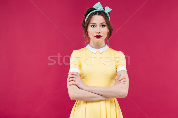 Beautiful serious woman in yellow dress standing with arms cross Stock photo © deandrobot