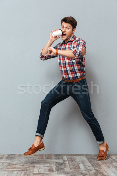 Shocked young man drinking takeaway coffee and running Stock photo © deandrobot