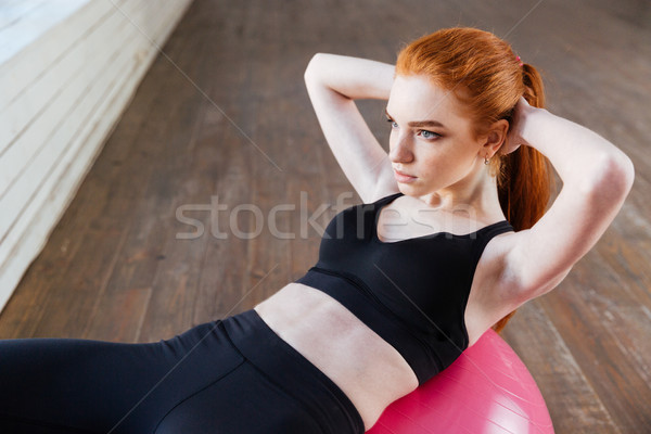 Beautiful young girl doing exercises with fit ball at gym Stock photo © deandrobot