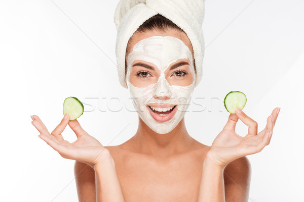 Stock photo: Woman with facial mask and cucumber slices in her hands