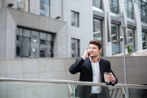 Happy young businessman talking on cell phone and drinking coffee Stock photo © deandrobot