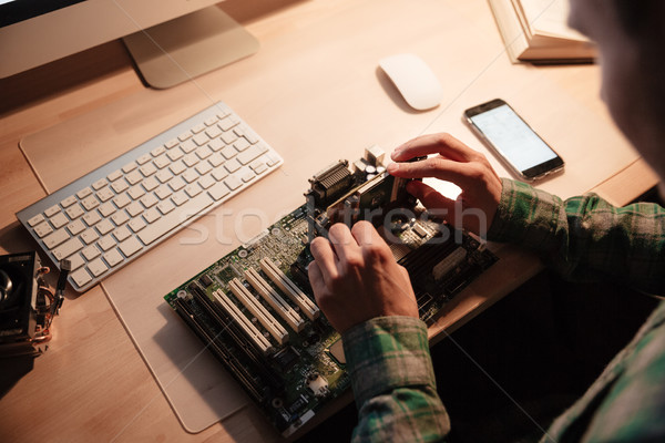Man sitting and repairing motherboard in the dark room Stock photo © deandrobot