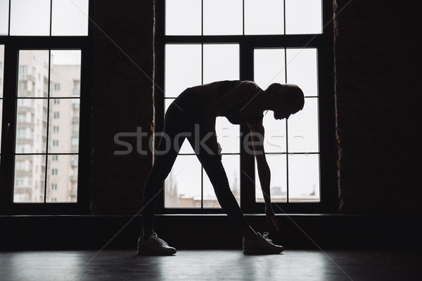 Silhouette of beautiful young sportswoman standing and working out Stock photo © deandrobot