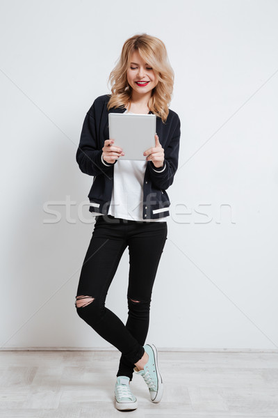 Smiling casual girl teenager standing and using tablet device Stock photo © deandrobot
