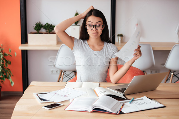 Confused woman indoors working with documents. Stock photo © deandrobot