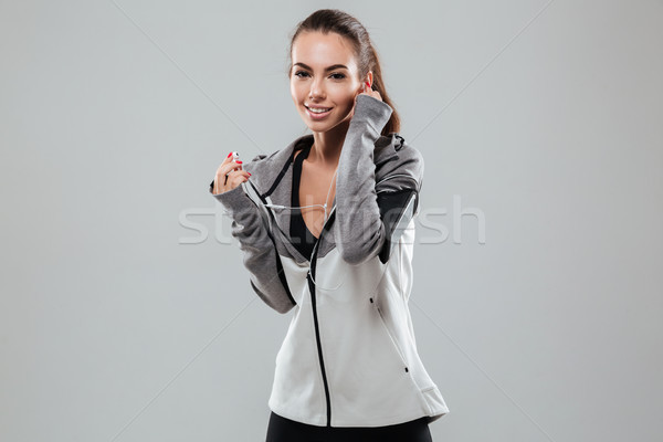 Smiling female runner in warm clothes listening music Stock photo © deandrobot