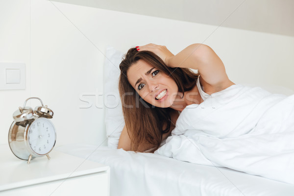 Annoyed angry woman laying in bed in the morning Stock photo © deandrobot
