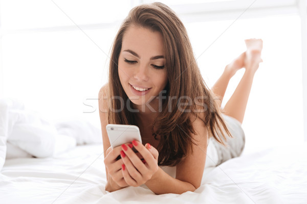 Close up portrait of smiling young woman using mobile phone Stock photo © deandrobot