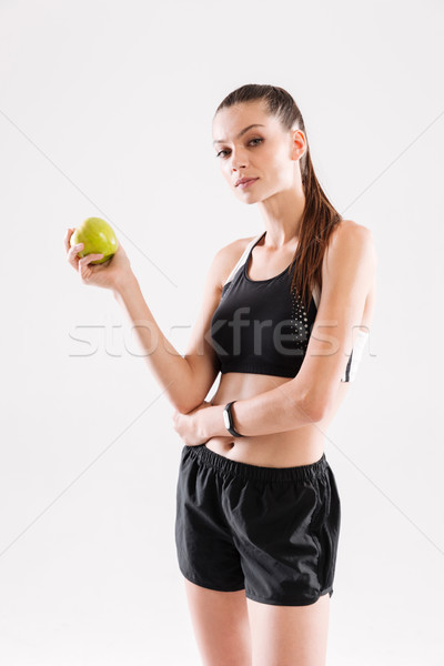 Stock photo: Portrait of a young attractive sportwoman holding green apple