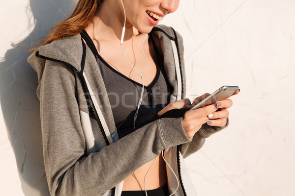 Cropped photo of young happy woman in sport wear using mobile ph Stock photo © deandrobot