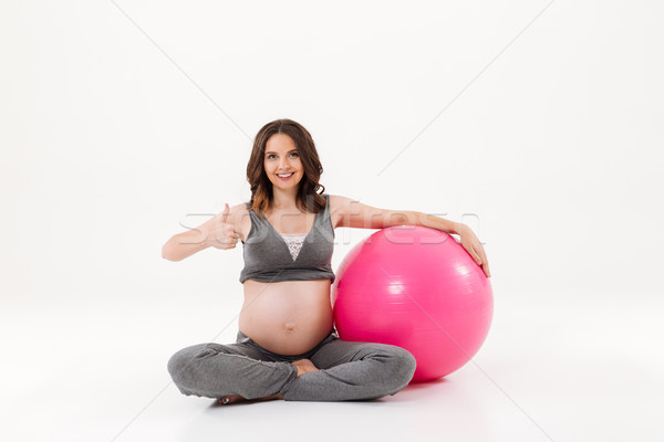 Smiling pregnant woman sitting on the floor with fitball Stock photo © deandrobot