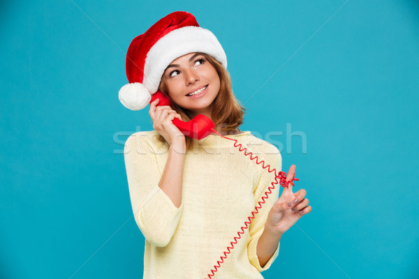 Close-up photo of beautiful young woman in Santa's hat playing with red cord while talking on retro  Stock photo © deandrobot