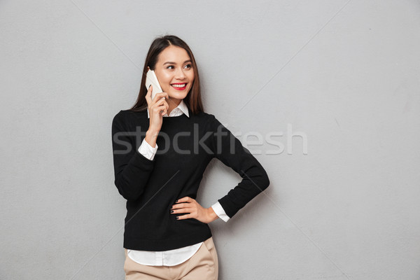 Smiling asian woman in business clothes with arm on hip Stock photo © deandrobot