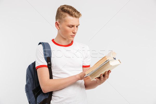 Image of young serious male student wearing backpack studying an Stock photo © deandrobot