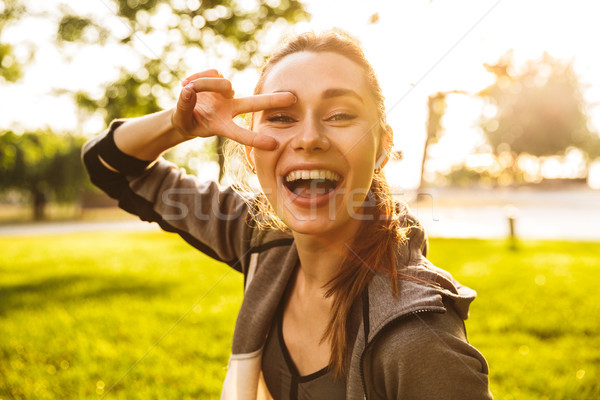 Photo of happy sporty woman 20s in sportswear wearing bluetooth  Stock photo © deandrobot