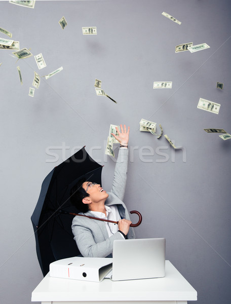 Businessman sitting at the table with rain of money Stock photo © deandrobot