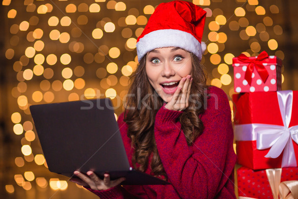 Wondered happy cute girl in santa claus hat using laptop  Stock photo © deandrobot