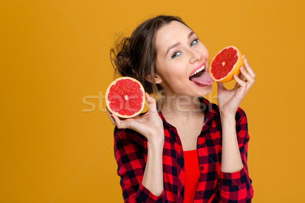 Happy attractive young woman holding and licking half of grapefruit  Stock photo © deandrobot