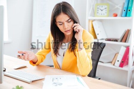 Businesswoman talking on the phone and analysing graphics Stock photo © deandrobot