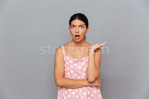 Portrait of a young amazed woman pointing finger away Stock photo © deandrobot