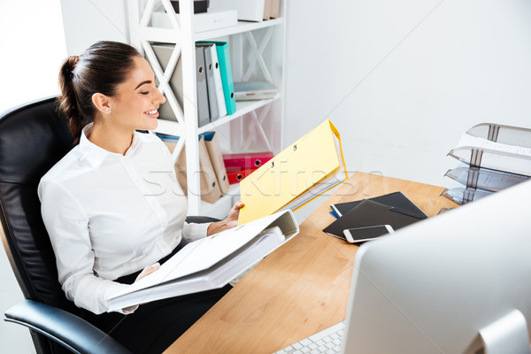Businesswoman holding yellow binders at office Stock photo © deandrobot