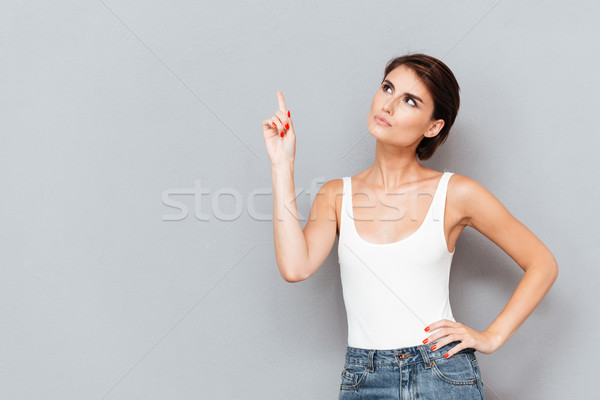 Poważny młoda kobieta wskazując palec w górę szary Zdjęcia stock © deandrobot
