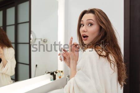 Woman looking at the mirror and touching lips in bathroom Stock photo © deandrobot