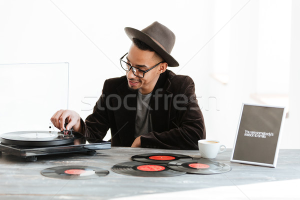 African man sitting by the table and using record-player Stock photo © deandrobot