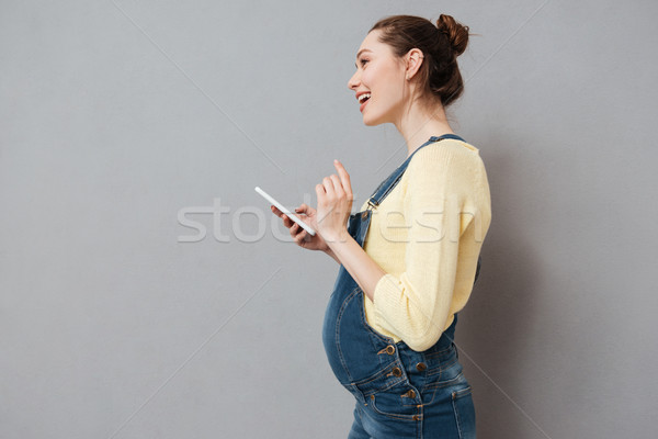 Oldalnézet fiatal terhes nő tart mobiltelefon csinos Stock fotó © deandrobot