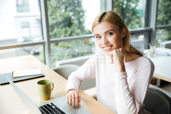 Cheerful lady sitting in office coworking while using laptop Stock photo © deandrobot