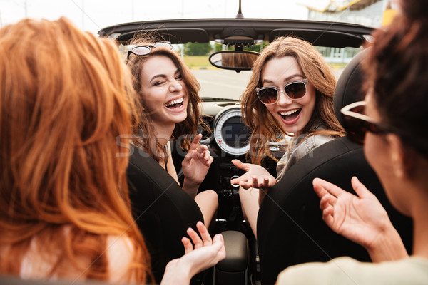 Smiling emotional four young women friends sitting in car Stock photo © deandrobot