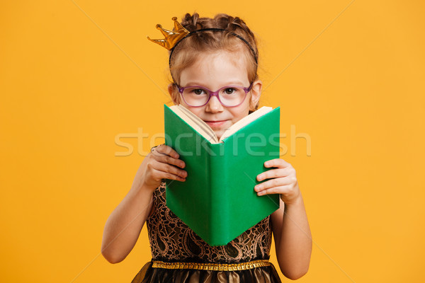 Cute girl child wearing princess crown reading book. Stock photo © deandrobot