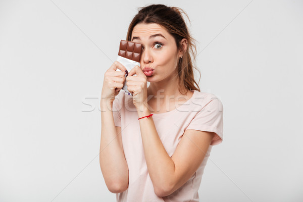 Portrait of a cute pretty girl holding chocolate bar Stock photo © deandrobot