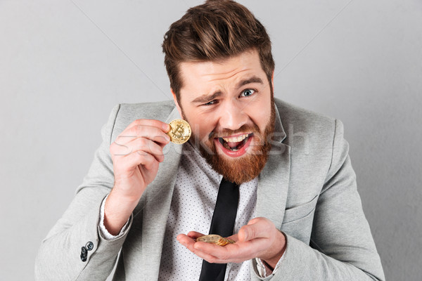 Portrait of a confident businessman showing golden bitcoins Stock photo © deandrobot