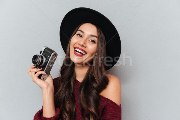 Pretty cheerful woman in black hat holding retro photo camera Stock photo © deandrobot