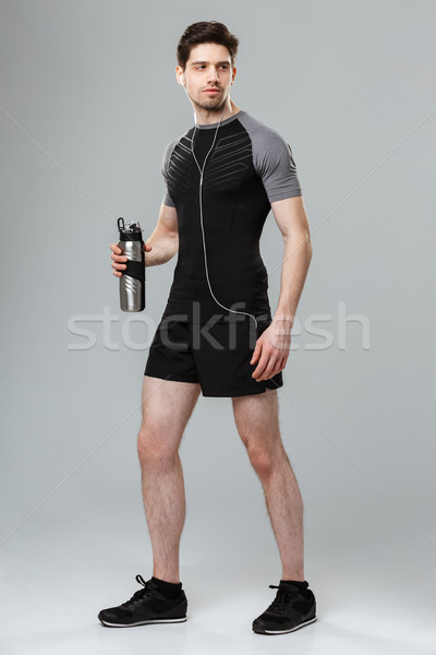 Handsome young sportsman holding bottle with water. Stock photo © deandrobot