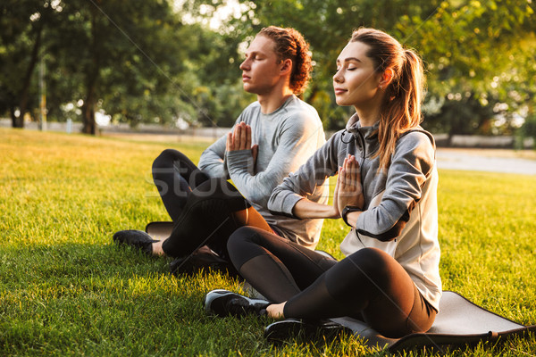 Fitness loving couple friends in park make meditate exercises. Stock photo © deandrobot