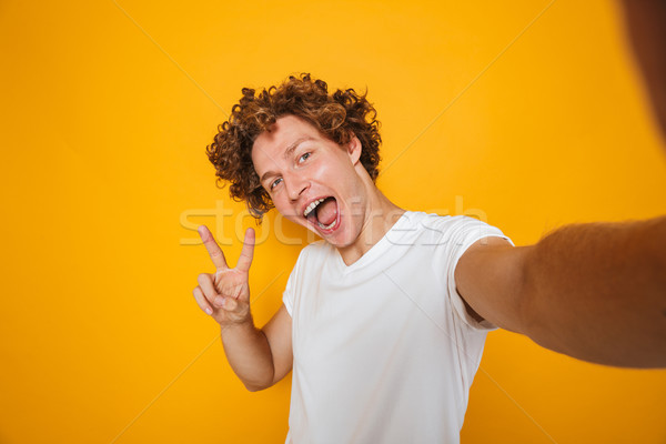 Good-looking caucasian man with brown hair showing peace sign on Stock photo © deandrobot