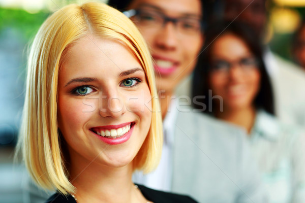 Portrait of a happy businesswoman standing in front of colleagues Stock photo © deandrobot