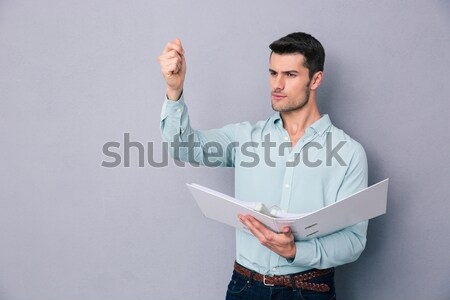 Man holding folder and pointing finger up Stock photo © deandrobot