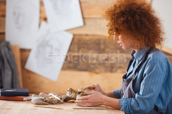 Focused woman ceramist creating sculpture using clay in pottery workshop Stock photo © deandrobot