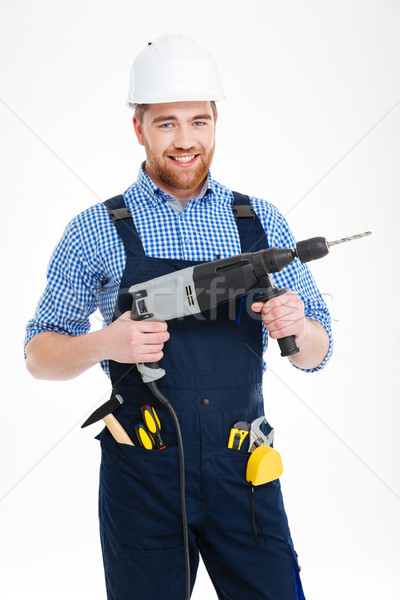 Portrait of cheerful attractive young builder in helmet with drill Stock photo © deandrobot